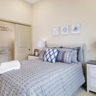 A cozy and well-decorated bedroom with a neatly made bed, nightstands, lamps, and minimalist wall art.