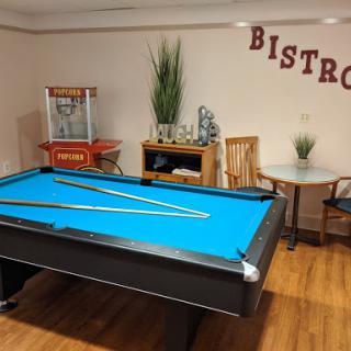A cozy game room featuring a vibrant blue pool table and a bistro corner.