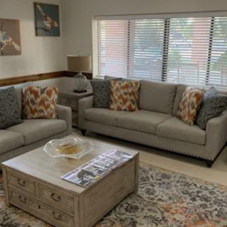 A cozy living room with two gray sofas, a wooden coffee table, and decorative elements including pillows and artwork.