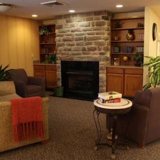 A cozy living room featuring a stone fireplace, comfortable seating, and bookshelves filled with books.