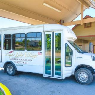 A white shuttle bus parked under a building canopy.