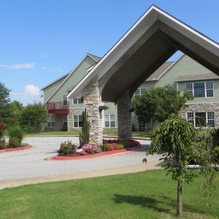 A welcoming building entrance with well-maintained landscaping and a driveway.