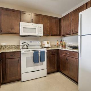 A modern kitchen featuring wooden cabinets and white appliances.