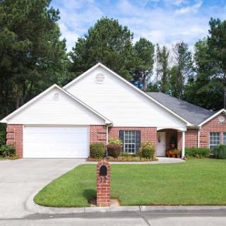 A charming single-story brick home with a well-maintained front yard and garage.