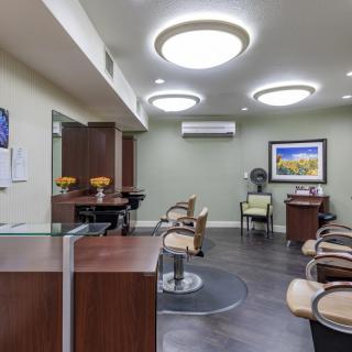 A modern salon interior with styling chairs, a reception desk, and contemporary lighting.