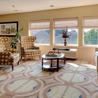 A cozy living room with patterned chairs, abundant natural light, and a central coffee table.