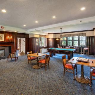 A cozy game room featuring a pool table, several seating areas, and a fireplace.