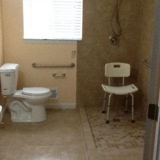 Accessible bathroom with a shower chair and grab bars.