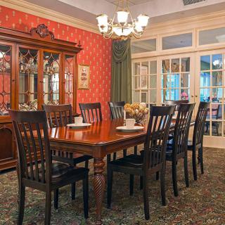 A traditional dining room with a long wooden table, matching chairs, and a chandelier.