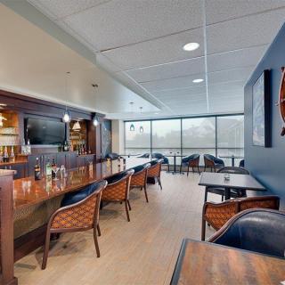 Modern bar interior with seating and large windows.