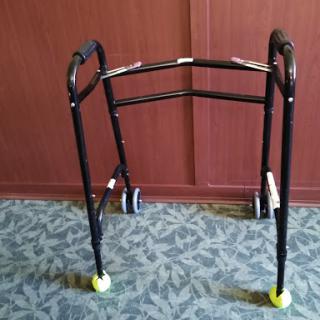 A black walker with wheels, designed to assist individuals with mobility.