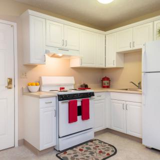 A cozy kitchen with white cabinets and red accents.