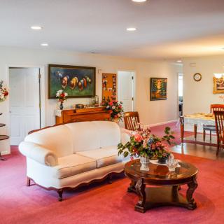 A cozy living room with vintage furnishings, highlighted by a white sofa and a wooden coffee table on a pink carpet.
