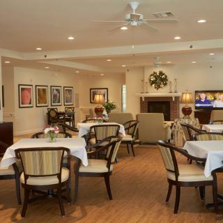 A cozy dining area with tables and chairs, featuring a fireplace and elegant decor.