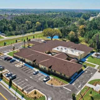 An aerial view of a large building complex surrounded by parking lots and lush greenery.