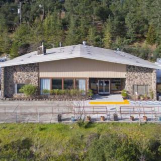A stone-clad building nestled against a forested hillside.