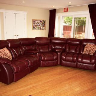 A cozy living room featuring a burgundy leather sectional sofa with decorative pillows.