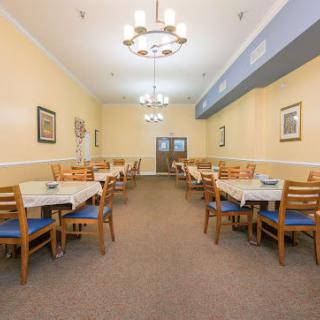 A well-lit dining room with multiple tables and chairs, decorated with wall art.