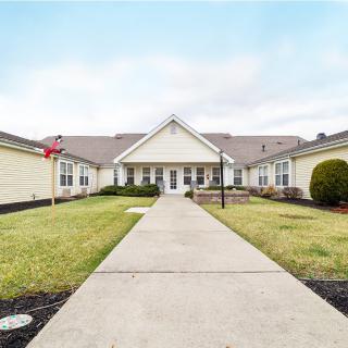 A wide walkway leads to the entrance of a symmetrical residential building, surrounded by well-maintained landscaping.