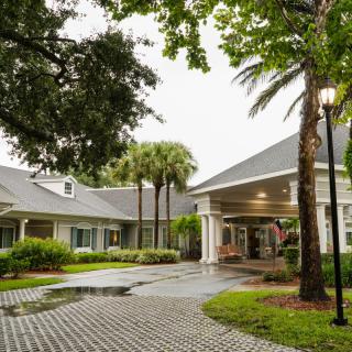 A charming residential building with a welcoming entrance, surrounded by lush greenery and palm trees.
