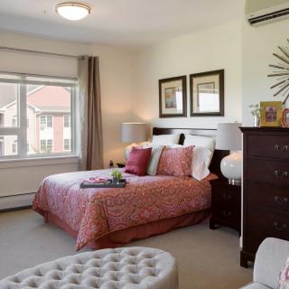 A cozy and well-decorated bedroom with a bed, dresser, and large window.