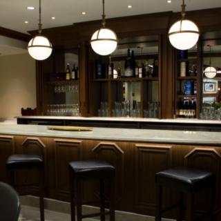 A stylish bar interior featuring a polished counter, modern lighting, and comfortable seating.