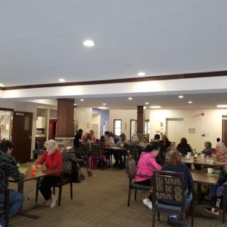 A group of people sitting and socializing in a dining hall.