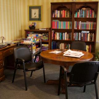 A cozy office setup with a round table, chairs, and bookshelves filled with books.