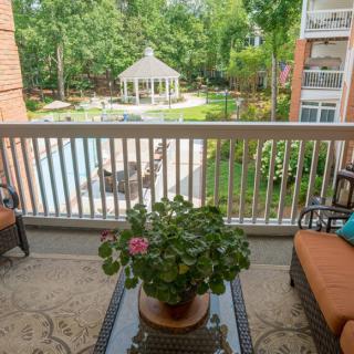 A peaceful balcony view overlooking a garden area with a gazebo and pool at an apartment complex.