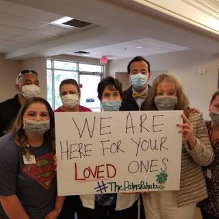 A group of caregivers holding a sign expressing their commitment to support loved ones.