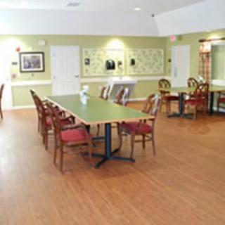 An empty dining area with wooden floors, tables, and chairs arranged neatly.