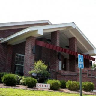 A brick building with a red awning and accessible parking sign in front.