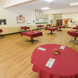 An empty restaurant dining area with tables covered in red tablecloths.