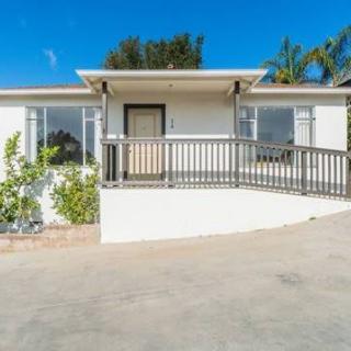 A single-story house with a front ramp and driveway under a clear blue sky.