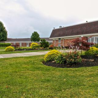 A well-maintained garden with lush green lawns and various shrubs in front of a brick building.