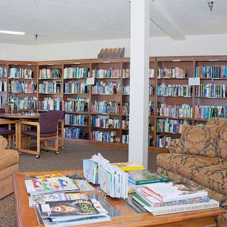 A cozy library with bookshelves, a reading area, and magazines on a table.