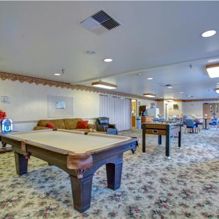 A spacious recreation room featuring a pool table, foosball table, and comfortable seating areas.