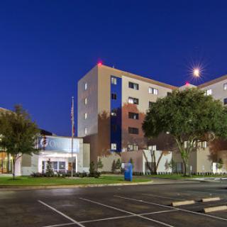 A modern hotel exterior illuminated at night, showcasing its architectural design and surroundings.