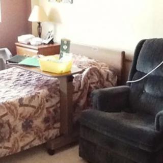 A cozy bedroom with a bed, recliner, and nightstand.
