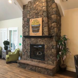 A cozy living room featuring a stone fireplace, comfortable seating, and decorative elements that create a warm atmosphere.