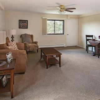 A cozy living room with comfortable seating, a coffee table, and a ceiling fan.