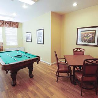 A cozy game room featuring a pool table and a seating area with framed pictures on the walls.