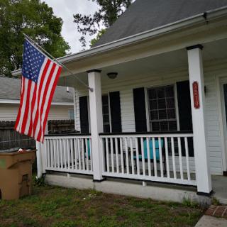 A charming home with an American flag proudly displayed on the porch.