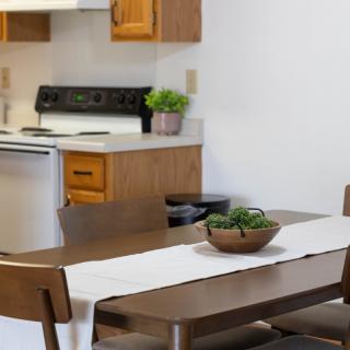 A cozy kitchen and dining area with a wooden table, chairs, and a stovetop in the background.