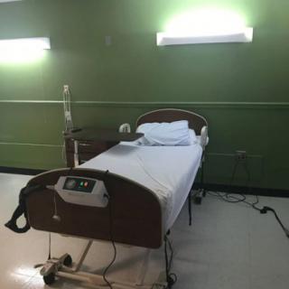 An empty hospital room with a single bed and medical equipment.
