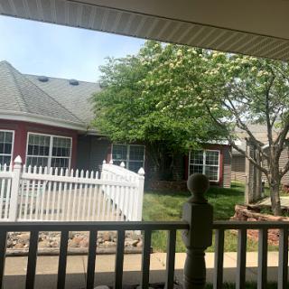 A peaceful view of a residential home with a white picket fence and a tree in the front yard.