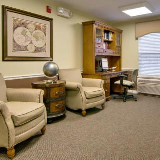 A cozy office space with chairs, desk, bookshelf, and a globe.