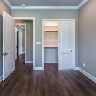 An empty room with wood flooring, featuring a closet and two doors.