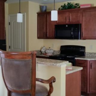 A kitchen interior featuring wooden cabinets, a countertop with bar stools, and modern appliances.