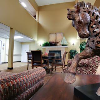 A cozy lobby featuring a wooden horse sculpture, comfortable seating, and a fireplace.